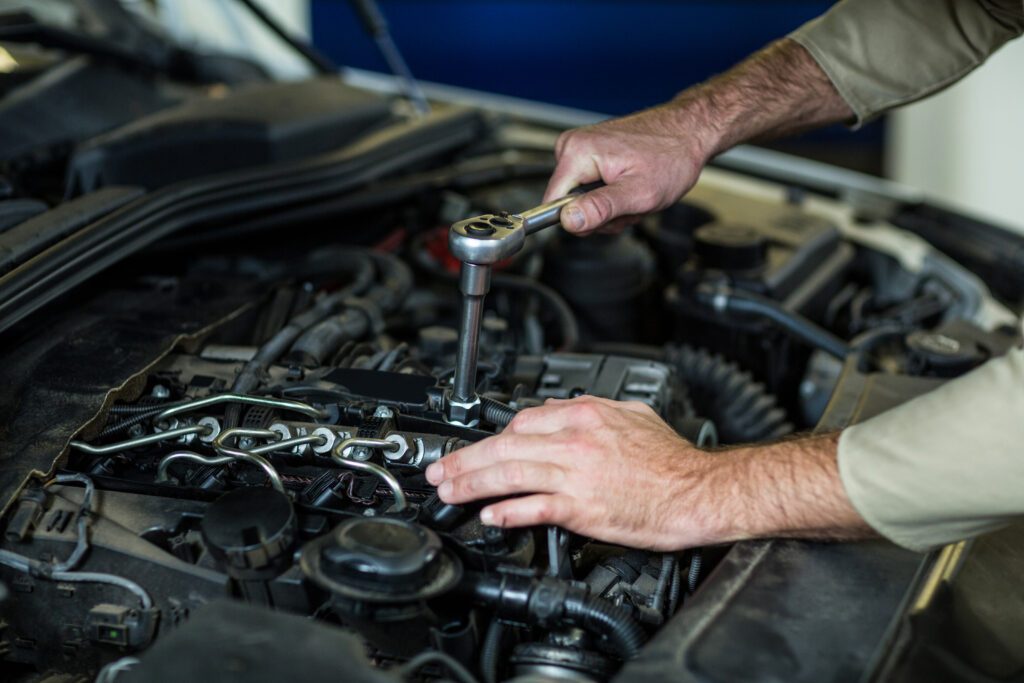 Hands of mechanic servicing a car in repair garage